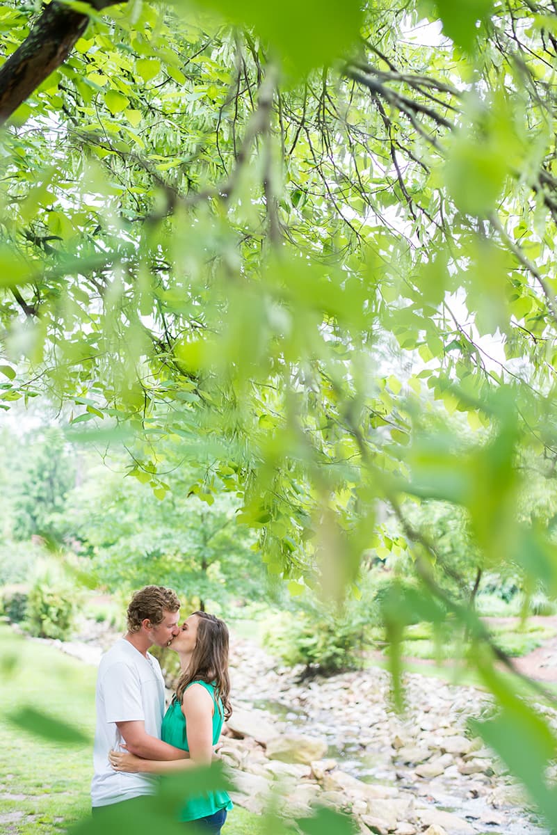 Couple kissing under a tree for engagement photo session