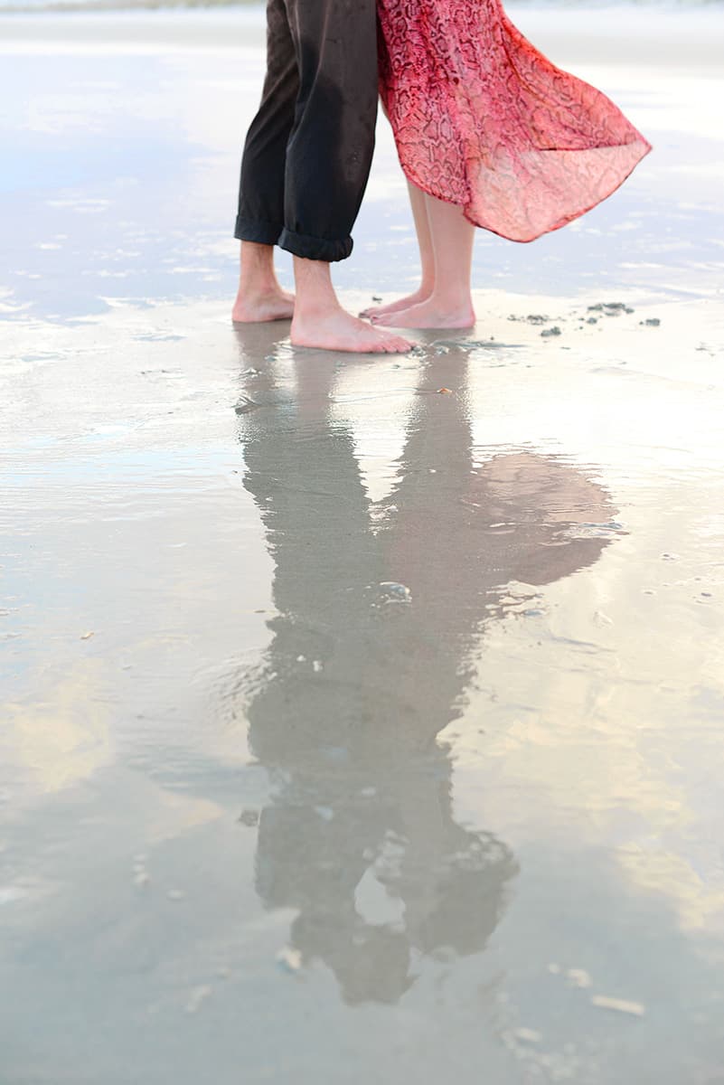 Engagement picture with couple reflecting in the water on a beach